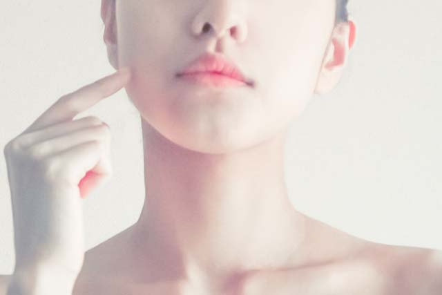 頬を指差す女性